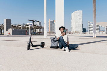 Stylish guy with phone and electric scooter in town