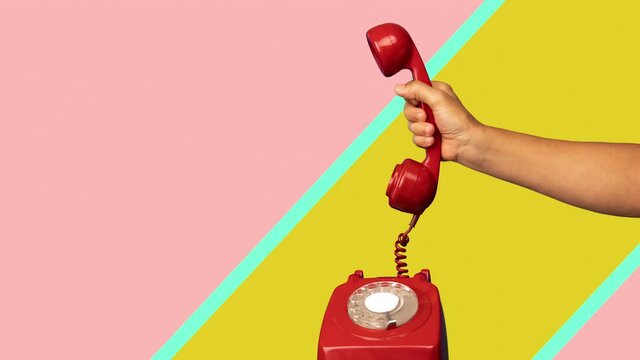 Hand holding the receiver of a retro red telephone