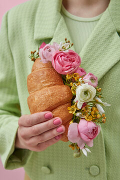 Closeup of woman holding croissant with peonies