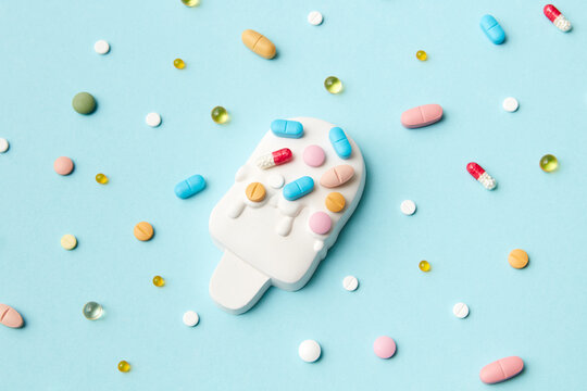 Colored pills on ice cream and blue background