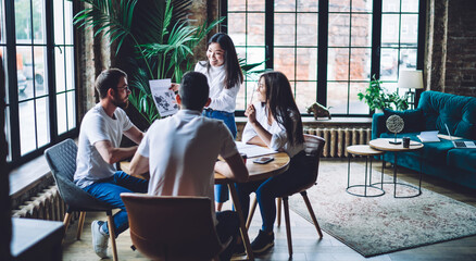 Cheerful hipster guys laughing while discussing business plan during collaborative meeting for together brainstorming, group of friendly students enjoying time for analyzing course work reports