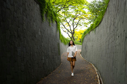 singaporean walking between wall with book