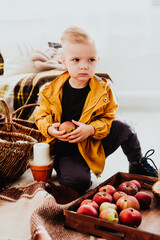Cool trendy hipster boy 2 years old wears yellow jacket posing at the decorated photozone of autumn decor with beautiful bright autumn leaves.