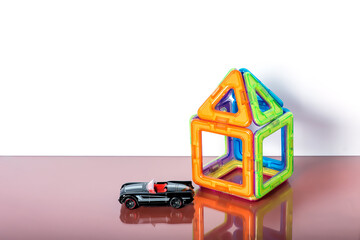 Fototapeta premium children's magnetic designer for development of motor skills, thinking and imagination. construction assembled with a small car on white