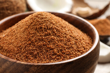 Natural coconut sugar in wooden bowl on table, closeup