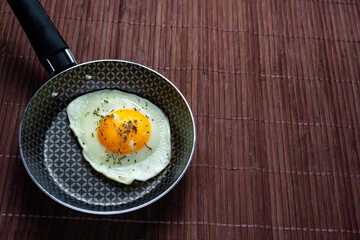 Frying pan with fried egg on a bamboo table