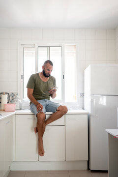 Moden man using his phone at kitchen