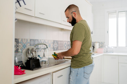 Hipster man washing in the skin at kitchen