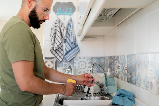 Young man washing in the skin at kitchen