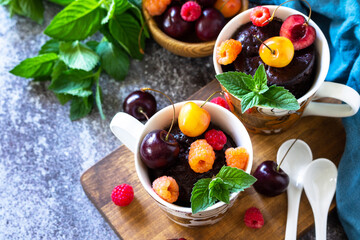 Fototapeta na wymiar Summer breakfast or dessert. Chocolate cupcake in a mug is served with fresh summer berry raspberries and cherries. Copy space.