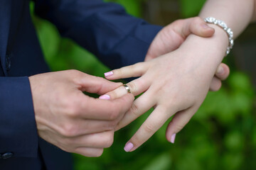 hands close-up, the groom puts a ring on the bride's finger