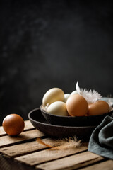 Chicken eggs with feathers in a basket on rustic background. Rustic style