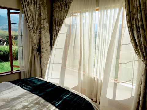 Cutains floating on a breeze into a peaceful bedroom