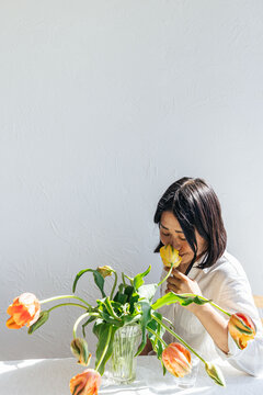 Young woman smelling tulips in a vase