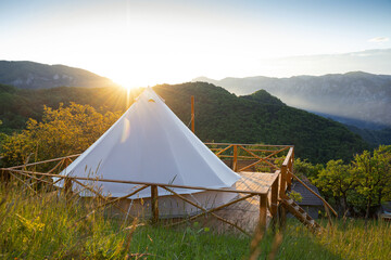 glamping tent in the morning sunlight with mountain range panorama