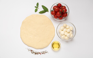 Raw dough and other ingredients for pizza on white background, top view