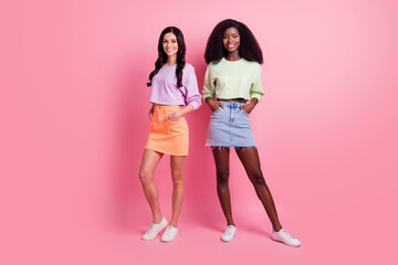 Full body photo of charming cute young women hold hands pockets good mood isolated on pastel pink...