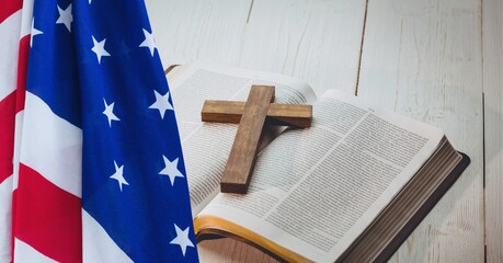 American flag over wooden cross over bible against wooden background