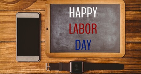 Happy labor day text over wooden slate, smartphone and watch on wooden background