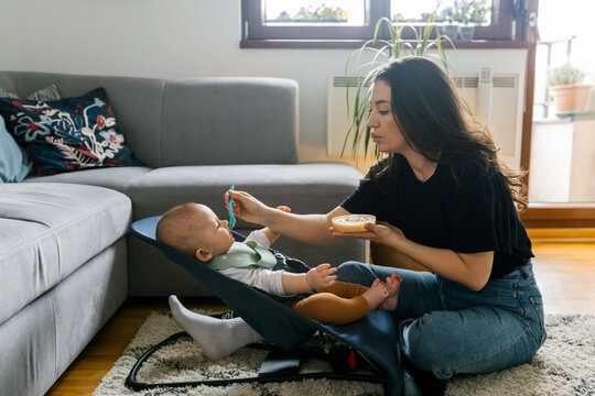 Family lifestyle, young millennial mom feeding her baby 