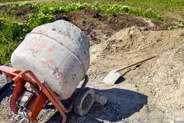 Mobile concrete mixer on background of pile of gravel. Preparatory work for preparation of concrete...