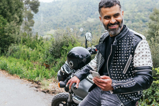 Stylish male biker browsing smartphone in nature
