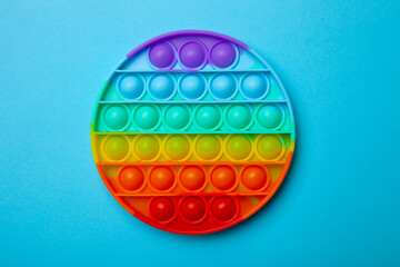 Simple dimple or pop it game on blue background. Top view of Push Pop Fidget Toy on color background. Silicon sensory anti stress toy