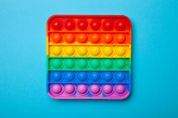 Simple dimple or pop it game on blue background. Top view of Push Pop Fidget Toy on color background. Silicon sensory anti stress toy