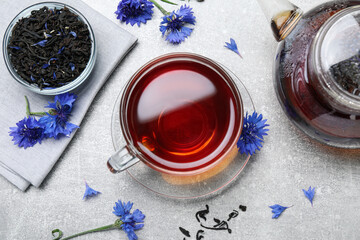 Flat lay composition with tea and cornflowers on light table - obrazy, fototapety, plakaty