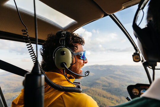 Passenger and pilot of a helicopter flying over the mountains