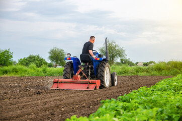 A farmer is cultivating a farm field. Milling soil, crushing before cutting rows. Loosening...