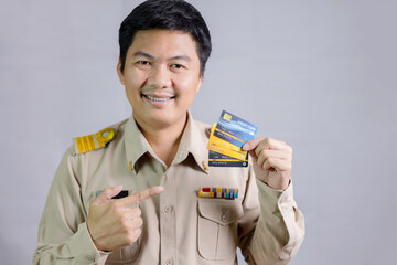 Thai government teacher, stands holding a replica of a credit card