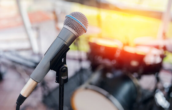 Electronic Microphone On Background Of Musical Instruments Drums With Glare Of Sun, Concept Of Summer Vacation Concert