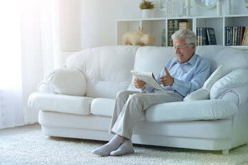 Senior man reading newspaper  at home