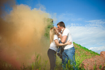 Happy family of three on a background of colored smoke in summer