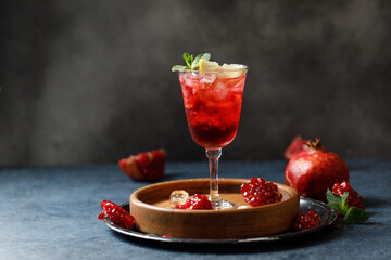 Pomegranate refreshing summer cocktail on dark background. Summer cocktail