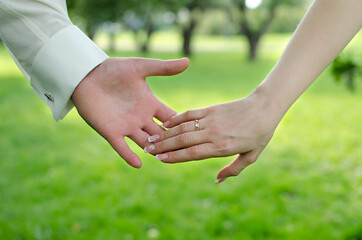 Loving  young couple holding hands in a green field. 