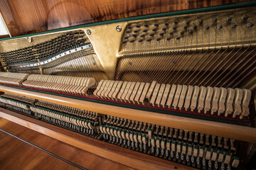 Open upright piano mechanism with strings and hammers. Selective focus.