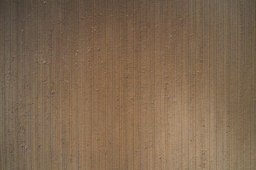 Plowed land aerial view. Cultivated soil top view. Brown ground, view to great heights. Preparing the soil for planting plants.