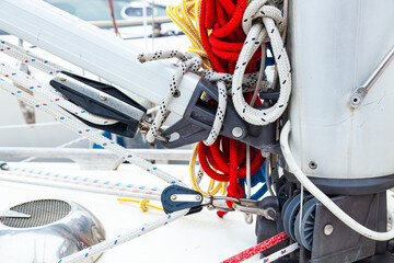 Part of the mast and hull of a sailing yacht, with multi-colored ropes, rollers and hinges for securing sails
