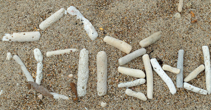  Sand with white pieces of dead coral on the beach of Curacao. It looks like an unknown script. It seems to be Papiamento. Pabien is written upside down which means 'Happy Birthday'