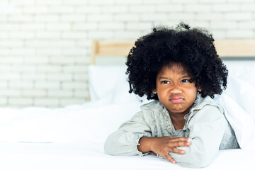 Portrait images of African girl 5-years old, Lying in the white bed Showing face Depicting anger and resentment, concept to Children with emotional expressions.
