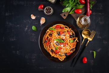 Spaghetti alla puttanesca - italian pasta dish with tomatoes, black olives, capers, anchovies and basil. Top view, flat lay