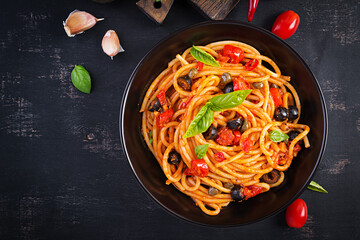 Spaghetti alla puttanesca - italian pasta dish with tomatoes, black olives, capers, anchovies and basil. Top view, flat lay