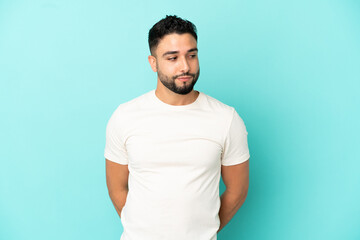 Young arab man isolated on blue background making doubts gesture looking side