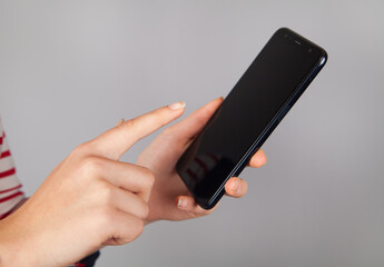 Young woman holding smartphone,  gray background.