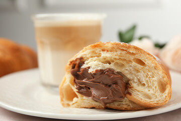 Half of tasty croissant with chocolate on plate, closeup. Space for text