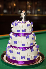 white wedding three-story cake with purple butterflies and purple ribbon