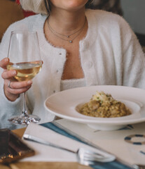 Mujer comiendo un risotto de verduras y bebiendo una copa de vino blanco