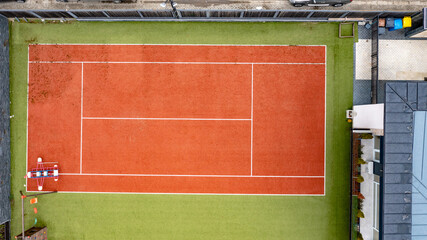 Aerial view of a red-green tennis court with black fences